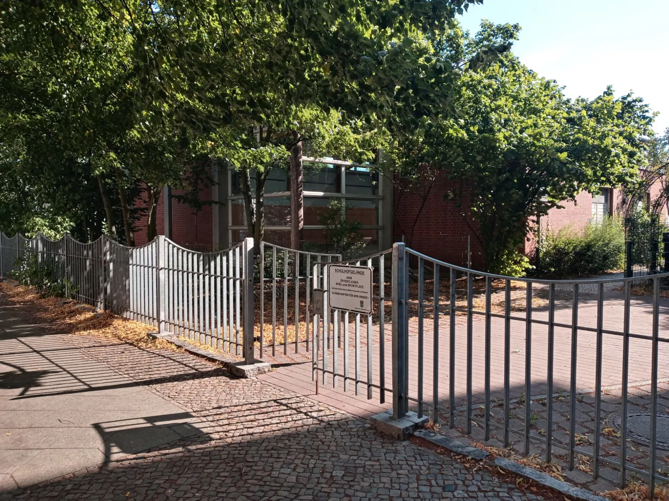 Außenansicht der Sporthalle der Edison-Grundschule mit dem Dojo des Kyokushinkai Karate Köpenick e.V. hinter einem Metallzaun.