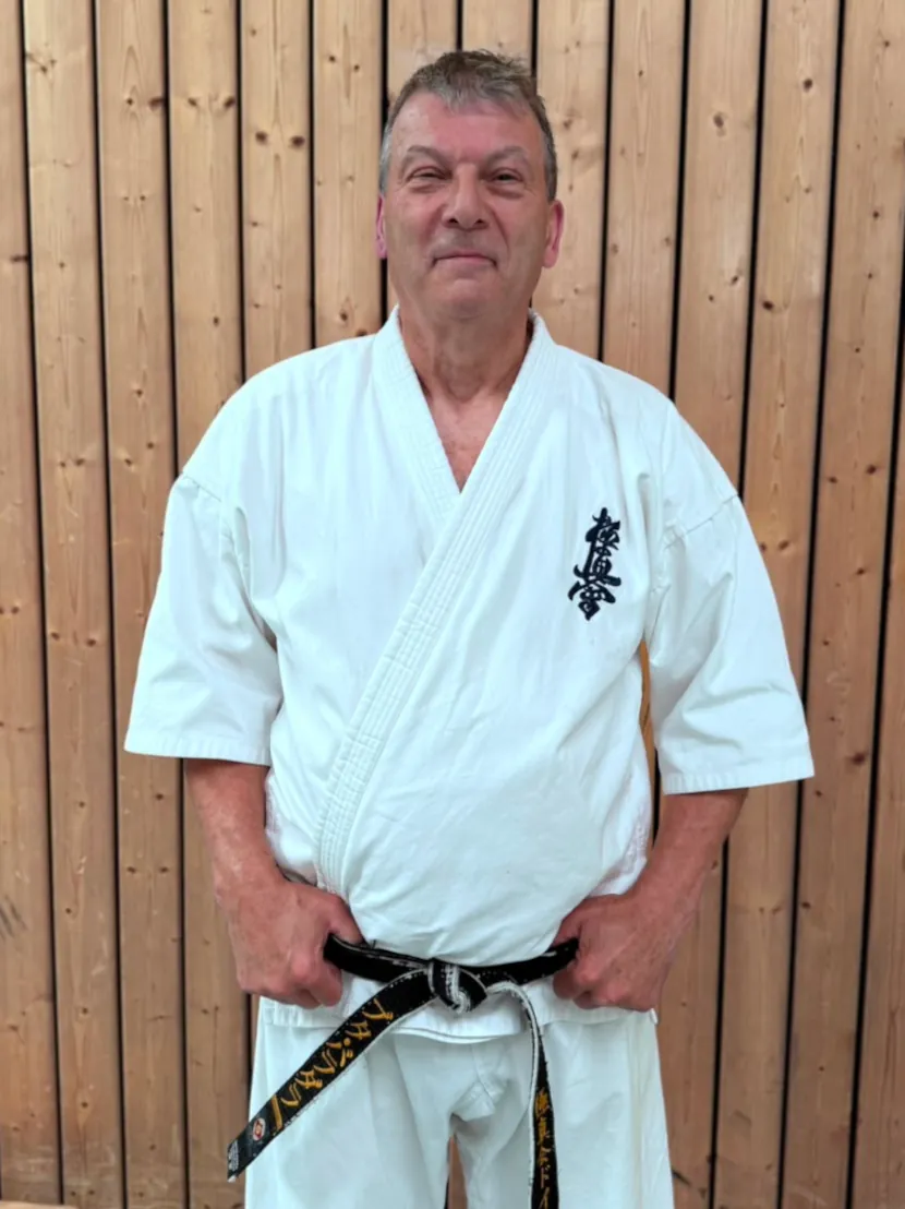 Senpai Peter Bradler, 1. Dan Kyokushin Karate, Trainer der Kyokushinkai Karate Köpenick e.V., vor einer Holzwand