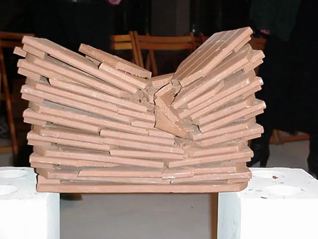 Bruchtest (Tameshiwari) mit Dachziegeln Ein großer Stapel brauner Dachziegel, die in der Mitte durch einen kraftvollen Karate-Bruchtest durchgeschlagen und zerbrochen wurden.