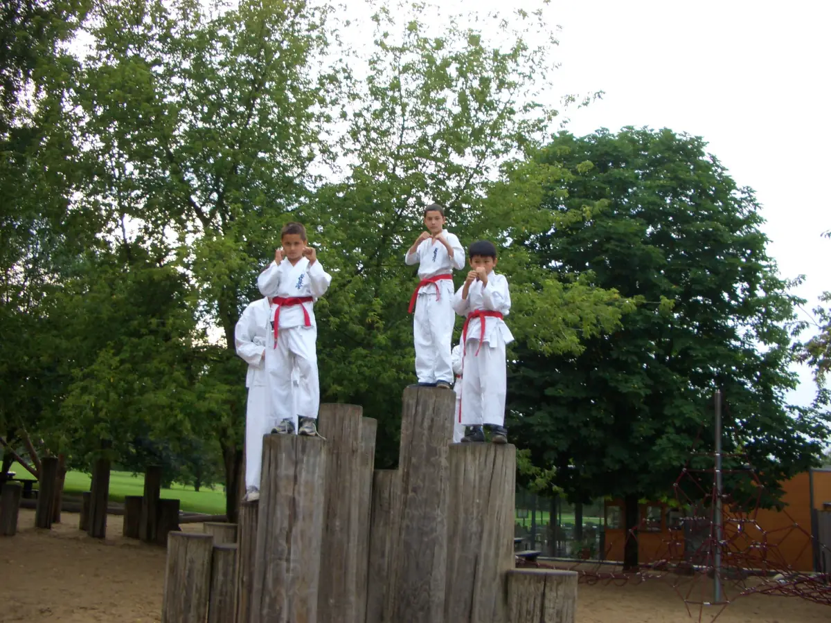 KKK e.V. – Gärten der Welt Kinder-Training (2007) Vier junge Karateka des Kyokushinkai Karate Köpenick e.V. beim Training auf Holzstämmen in den Gärten der Welt Berlin im Jahr 2007.