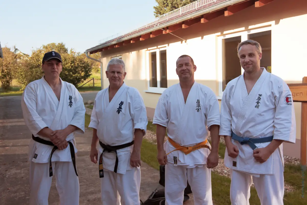 KKK e.V. mit Shihan Liam Keaveney (8.Dan – 2022) beim Oderlandcamp 2011 Vier Karateka im weißen Gi, darunter Shihan Liam Keaveney, stehen draußen vor einem Gebäude beim Oderlandcamp.