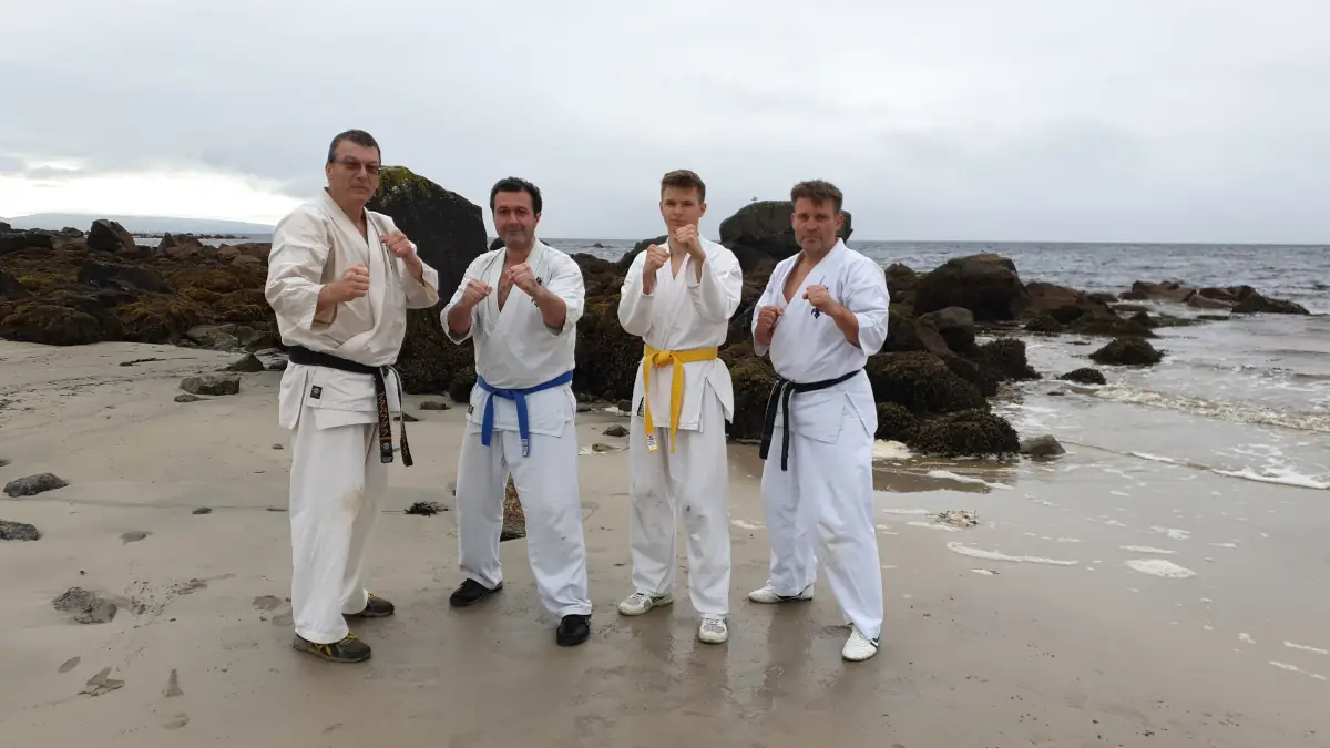 Team am Strand von Galway Team des Kyokushinkai Karate Köpenick e.V. steht direkt am Strand von Galway mit Felsen im Hintergrund
